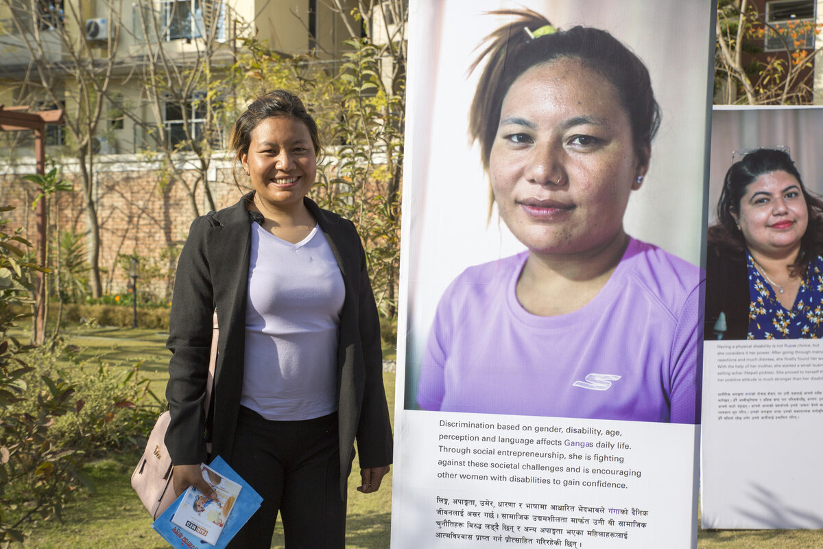 Eine Photovoice-Teilnehmerin steht neben ihrem Porträt während der Ausstellungseröffnung in Nepal. Foto: © CBM <br>
